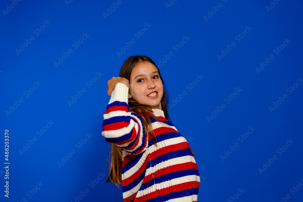 Profile shot of beautiful excited ambitious lady raising fist celebrating successful workout wearing striped sweater isolated over blue studio background. Profile shot of beautiful excited ambitious lady raising fist celebrating successful workout wearing striped sweater isolated over blue studio background.