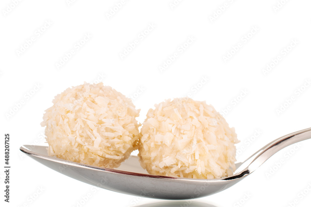 Two sweet coconut candies in a metal spoon, macro, isolated on a white background. Two sweet coconut candies in a metal spoon, macro, isolated on a white background.