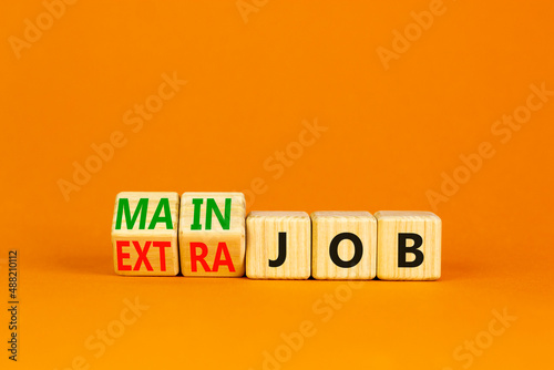 Extra or main job symbol. Turned wooden cubes and changed concept words Extra job to Main job. Beautiful orange table orange background, copy space. Business extra or main job concept.