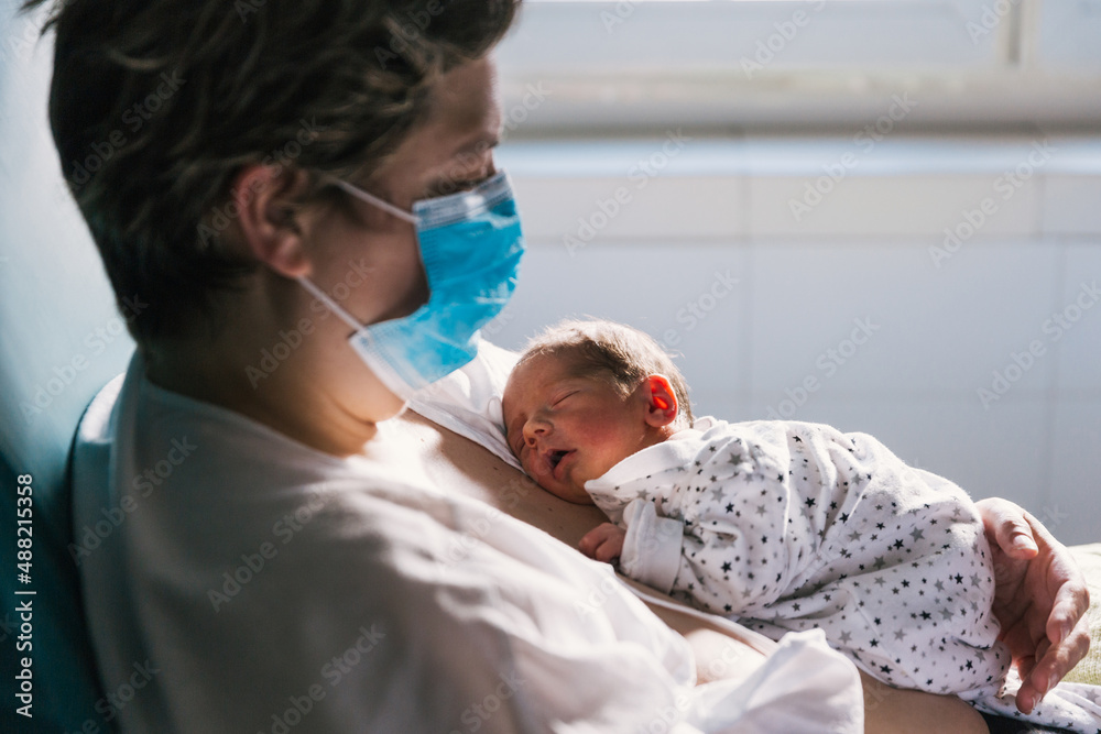 An adult woman in hospital bed holding newborn baby An adult woman in hospital bed holding newborn baby