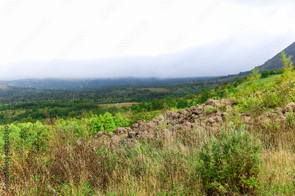 Epic mountain view with fog over the mountains and green grass and trees in valley Epic mountain view with fog over the mountains and green grass and trees in valley