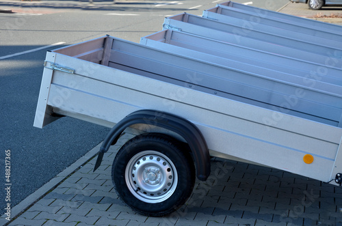trailer behind a car in the parking lot at the rental shop. just harness to the ball of the towing device. homologation and technical inspections. metal side panels photo