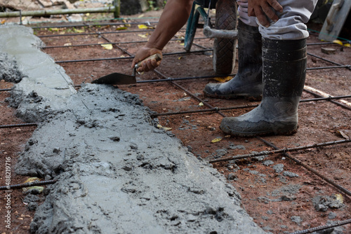 Hand of construction worker holding trowel while placing cement on floor. Construction concept. 