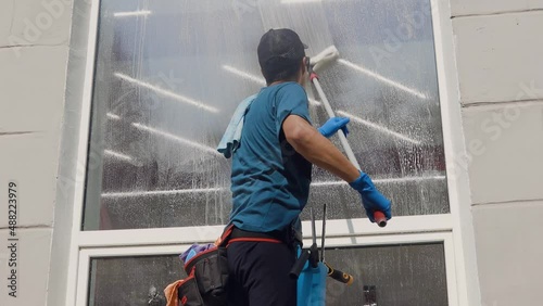 A professional cleaning service worker washes the windows with special foam and cleans them.