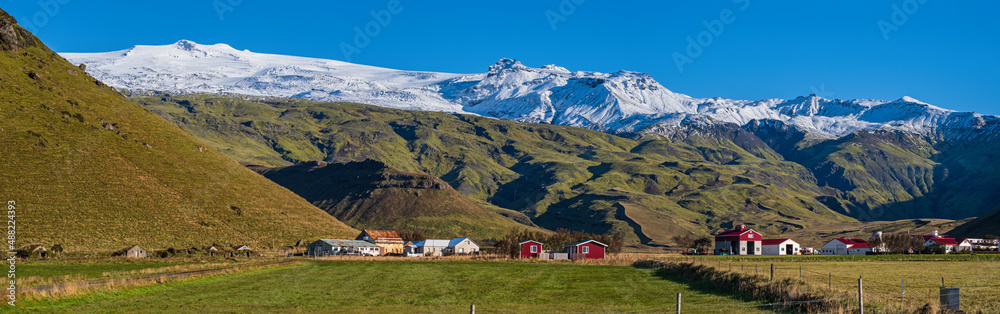 View from highway road during auto trip in Iceland. Spectacular Icelandic landscape with  scenic nature: hamlets, mountains, ocean coast, fjords, fields, clouds, glaciers, waterfalls.