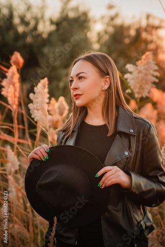 Stylish girl in a hat and leather jacket outdoors.