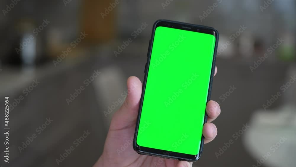Caucasian male holding phone with green screen display late at night in kitchen. Mock up chroma key surfing internet, watching content video Caucasian male holding phone with green screen display late at night in kitchen. Mock up chroma key surfing internet, watching content video