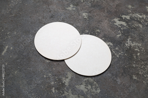 Two blank white beer coasters on concrete background. Responsive design mockup.