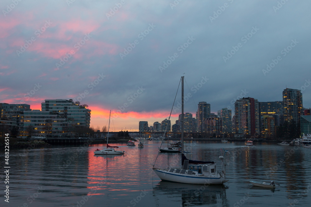 View of boats moored in False Creek seen during a beautiful blue hour sunset in winter, with cityscape in the background, Vancouver, British Columbia, Canada