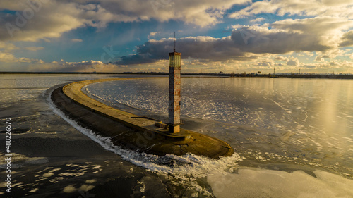 Aerial view of a pier with a lighthouse on a frozen lake