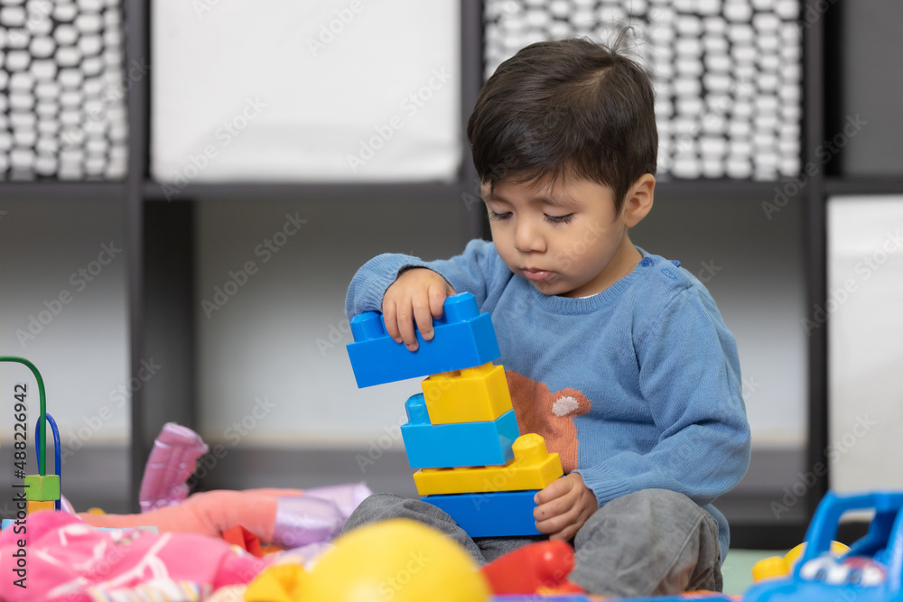two years old mexican baby boy playing with didactic toy on messy living room two years old mexican baby boy playing with didactic toy on messy living room