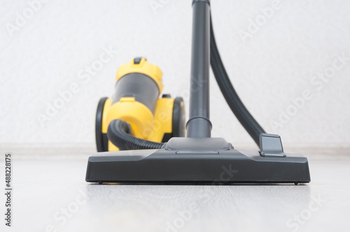 Vacuum cleaner with sweeping brush on wooden floor. Front focus