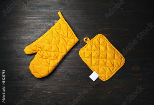 Oven mitt and potholder on wooden background. Kitchen accessory. Cooking mitten, oven-glove. Flat lay. photo