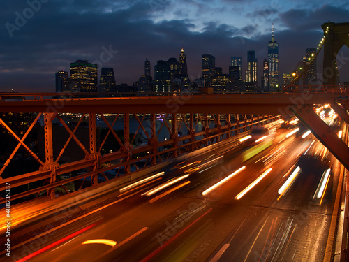 Long exposure shot of cars leaving Manhattan via Brooklyn Bridge in New York at dusk