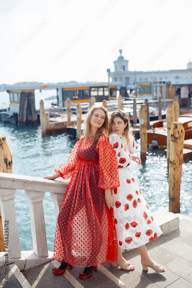 Naklejka premium Mom and daughter in fashionable dresses walk around Venice. Lifestyle, travel, tourism.