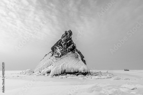 Lonely rock - an island on Lake Baikal under a layer of ice and snow