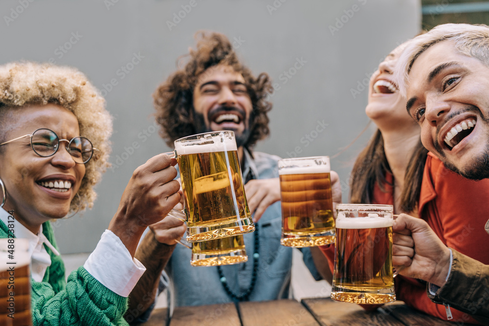 Multiracial friends having fun cheering with beers at brewery bar restaurant outdoor - Focus on african girl hand Multiracial friends having fun cheering with beers at brewery bar restaurant outdoor - Focus on african girl hand