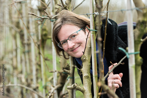  Young woman in winter clothes posing between low fruit trees photo