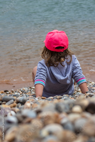 Girl in pink cap on pebble beach