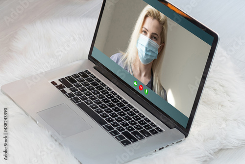 woman in mask talking online on laptop.