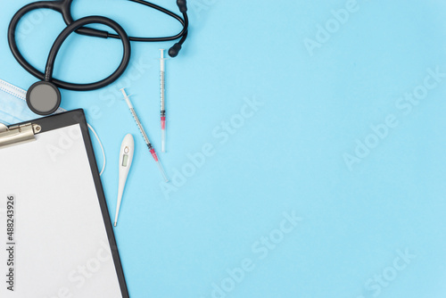 Blank paper, thermometer, disposable syringes on a blue background. Medical business cover and banner concept.
