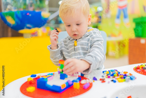 little boy play colorful cubes puzzle at the table