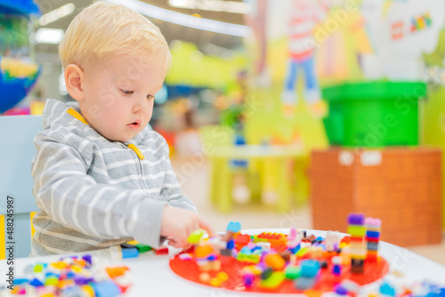 little boy play colorful cubes puzzle at the table