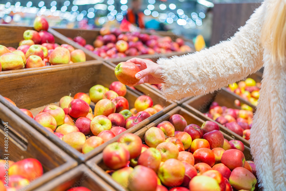 female hands take apples in a store in wooden boxes