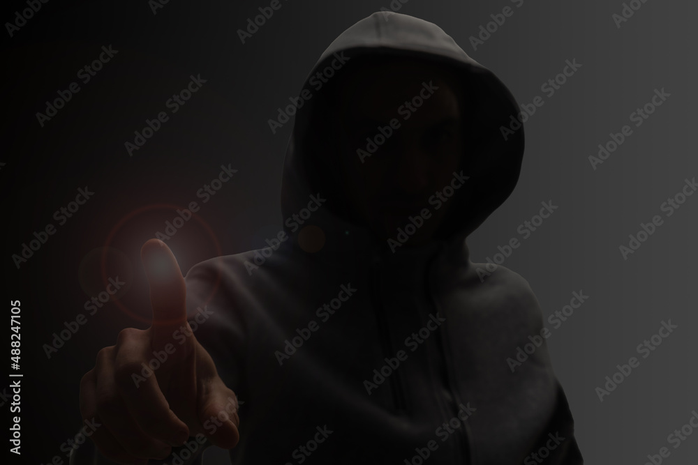 Close up portrait of a courageous man in a deep dark hood on a black background. The concept of secrecy of secrets and people hiding from the government. Hackers and thieves. Low key.
