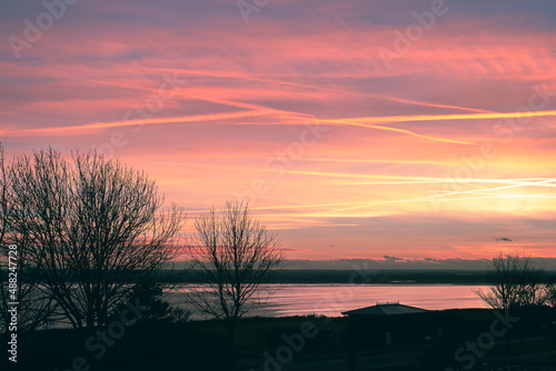 A beautiful pretty sky at dusk over a bay of water. The pink colour of the sky is reflecting in the sea.