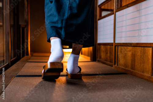 Japanese ryokan machiya traditional house with man in kimono back behind closeup of legs feet with tabi white socks and geta shoes walking by shoji sliding paper door photo