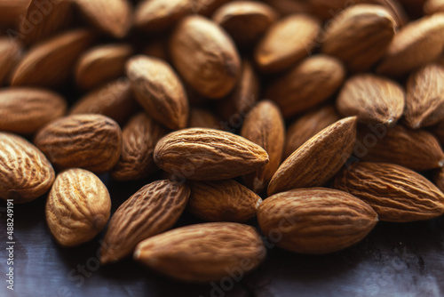 Close up almonds on dark wooden table. Organic health protein vegetarian food. Background copy space