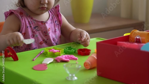 Sculpture and clay modeling for children. Girl 2-5 years old forming and shaping pink play dough by fingers and plastic modeling knife. Enhancing fine motor skills and kid creativity using play clay