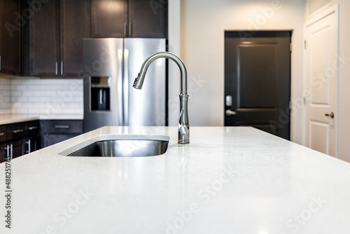 Kitchen room quartz countertop surface island in modern apartment home house by cabinets refrigerator fridge home appliance door entrance