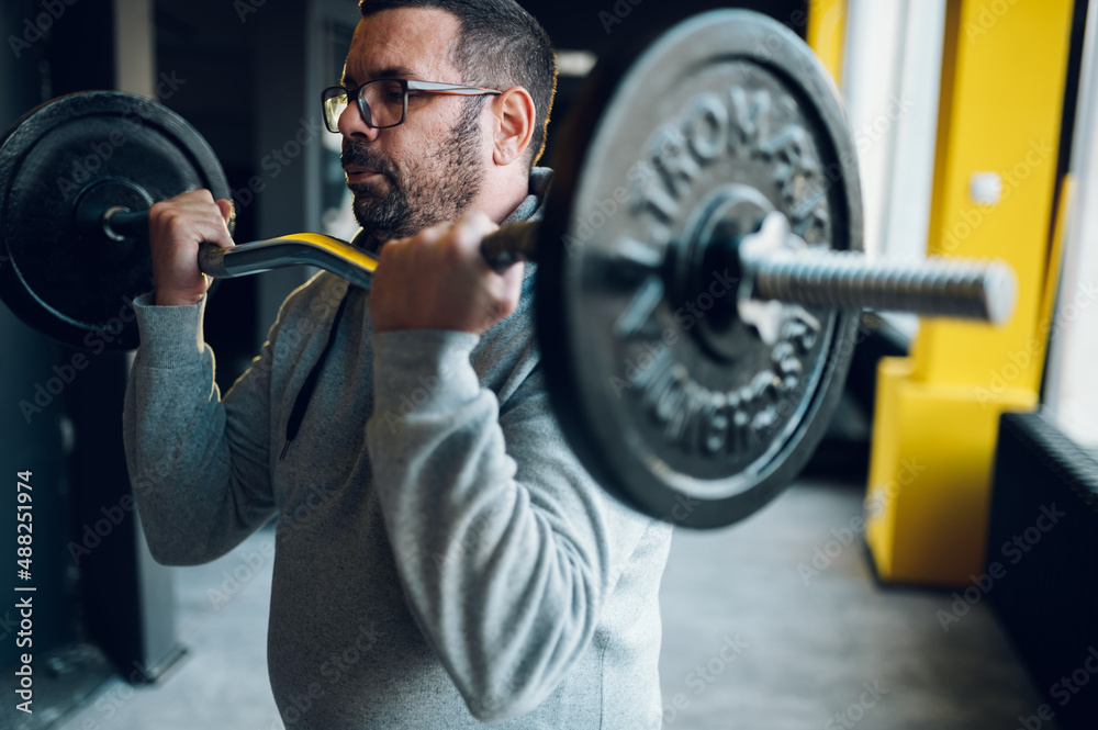 Middle aged man lifting barbell in the gym Middle aged man lifting barbell in the gym