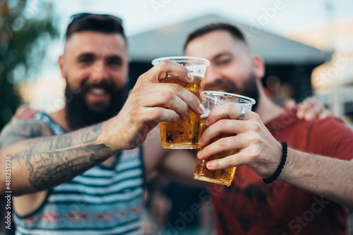 Two handsome friends drinking beer and having fun at music festival