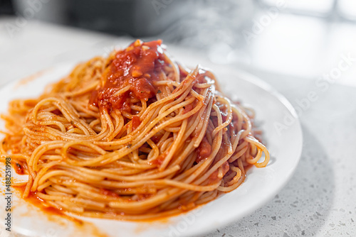 Red tomato sauce spaghetti pasta noodles closeup on plate in marinara sauce with hot steam rising