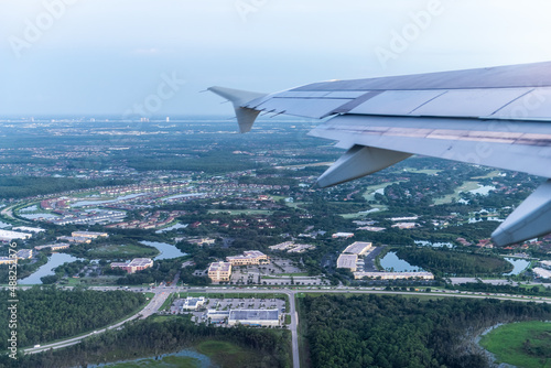 Airplane flying taking off with window aerial point of view of Fort Myers, Florida, USA city town houses and buildings in morning sunrise dawn