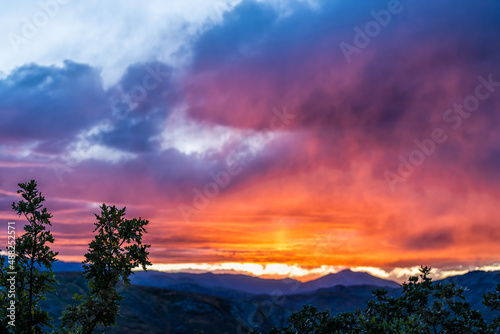Wide angle view of colorful dramatic sunset twilight blue hour at Aspen, Colorado rocky mountains peak and vibrant orange color light in blue sky skyscape and storm clouds