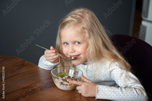 Little girl eating cereal in a bowl of milk