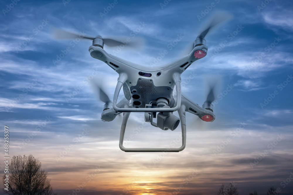 A drone flying at bright sunset on the background of cloudy sky. A drone flying at bright sunset on the background of cloudy sky.