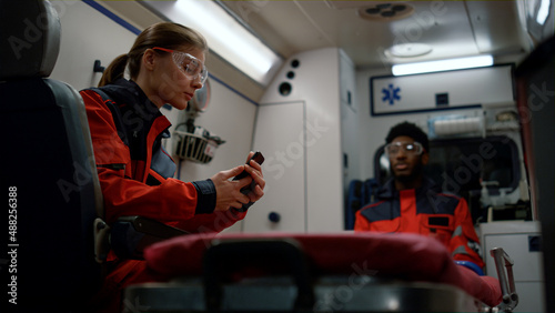 Emergency medical service talking in ambulance car. Doctors wearing uniform