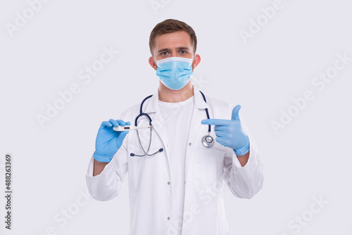 Doctor Showing Thermometer Wearing Medical Mask and Gloves Isolated. Man Doctor with Thermometer in Hands Pointing at It. Healthy Life, Doctor, Virus Concept