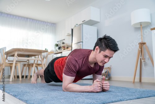 Asian handsome active young man doing exercise on floor in living room.
