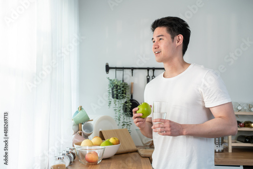 Asian attractive young male eating healthy foods in kitchen at home.  © Kawee