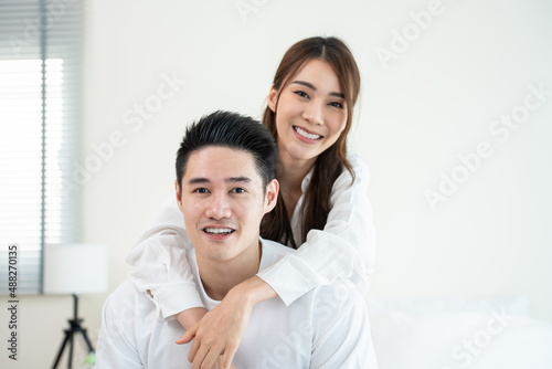 Portrait of Asian new marriage couple sit on bed and looking at camera. © Kawee