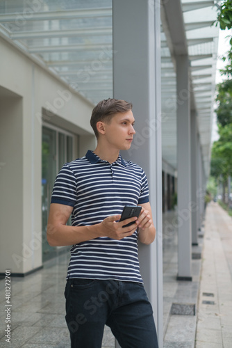Portrait of Young caucasian guy in casual clothing looking at his phone