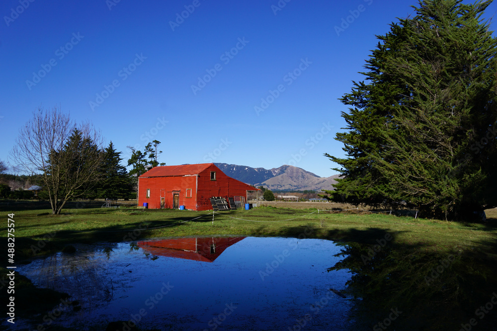 Obraz premium Abandoned red house in rural scenic mountainous landscape of New Zealand