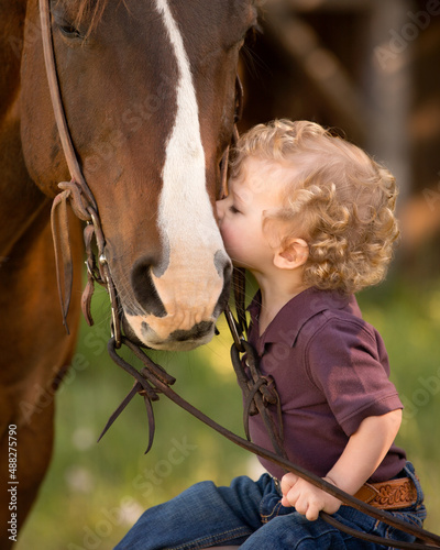 Young child kissing and interacting with horse