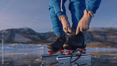 The child train on ice speed skating. Athlete puts on skates. The girl skates in the winter in sportswear, sport glasses. Children speed skating short long track, kid sport. Outdoor slow motion. photo